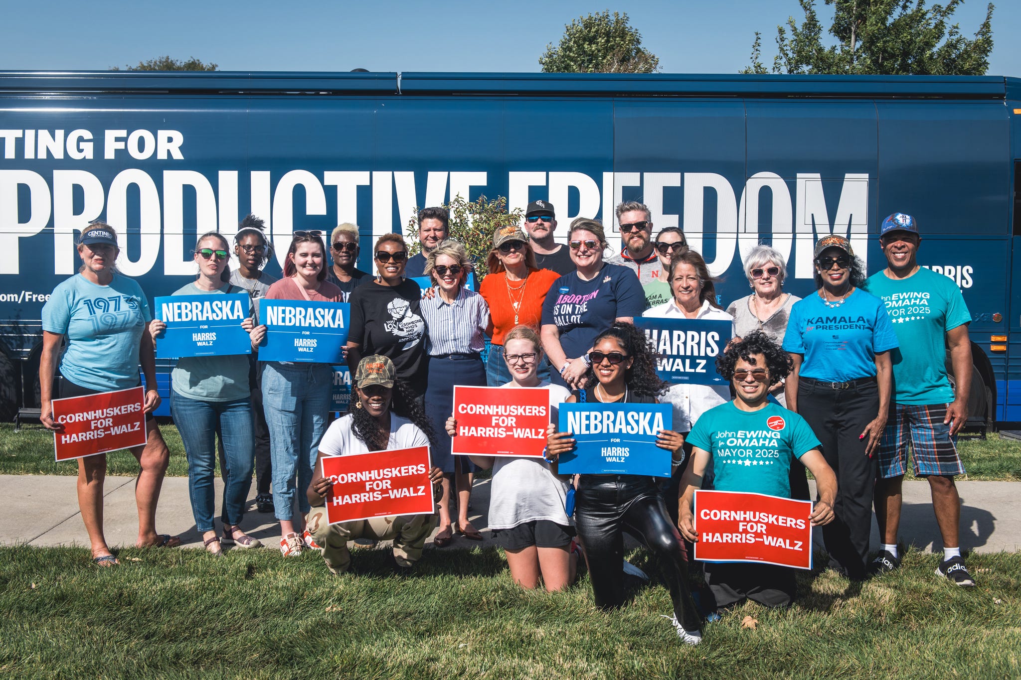 a group of supporters stands in front of a large blue bus