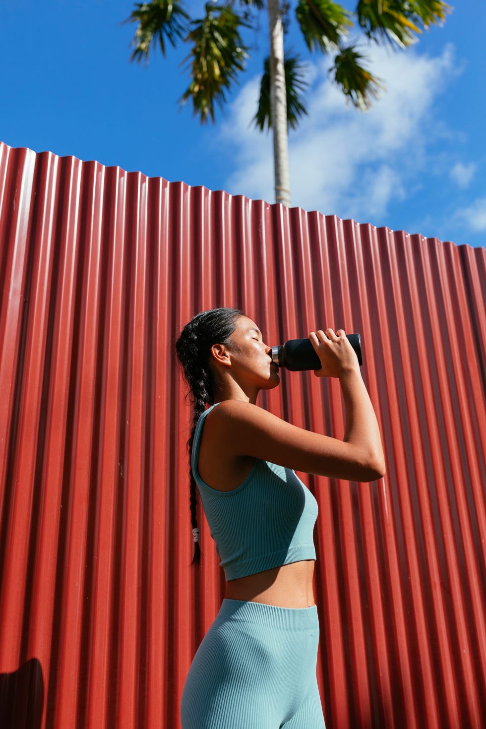 woman standing in front of the red wall and drinking water