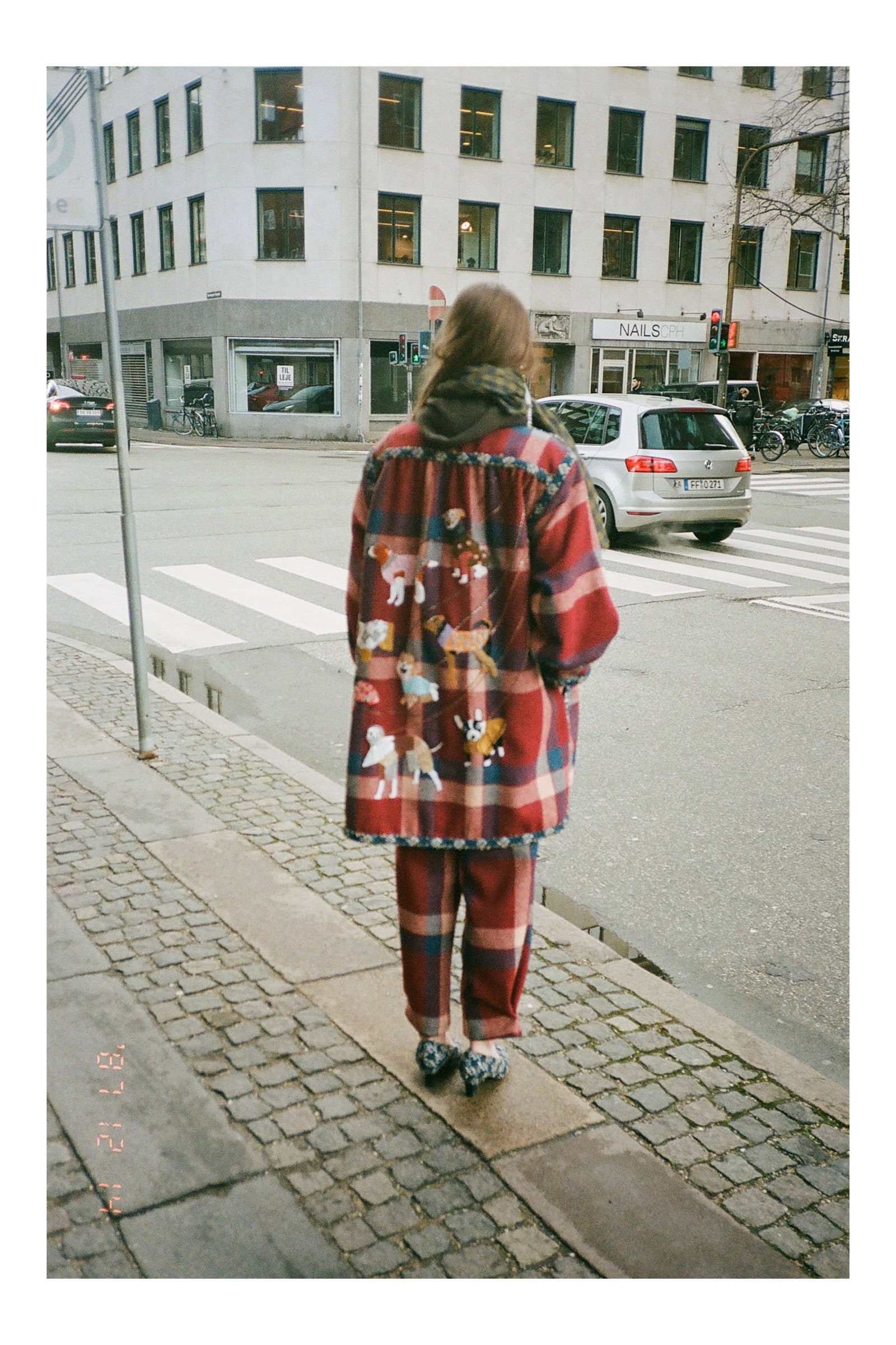 Image may contain City Road Street Urban Path Clothing Coat Adult Person Face Head Photography and Portrait